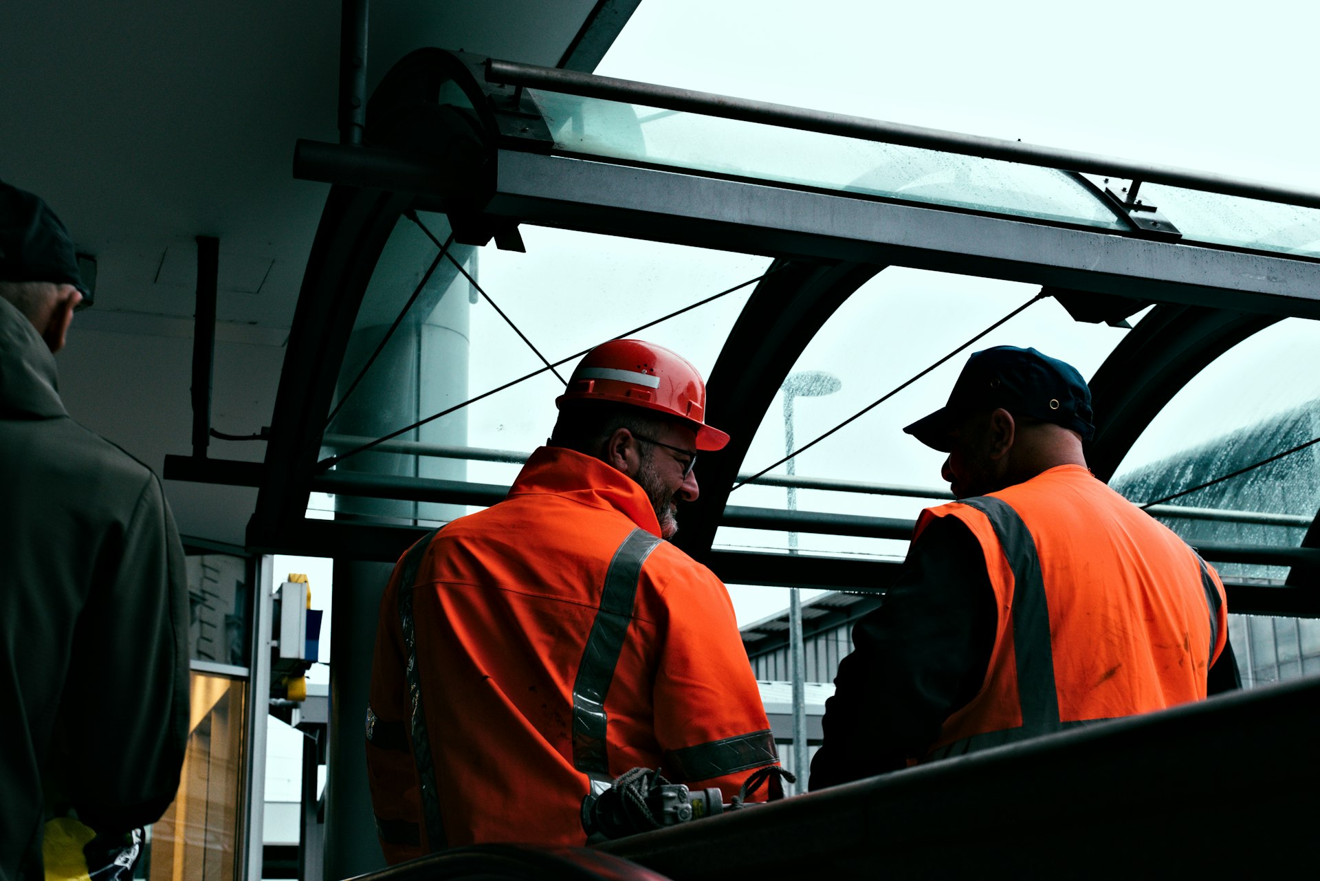 Two workers in orange hi-vis jackets chatting on the job