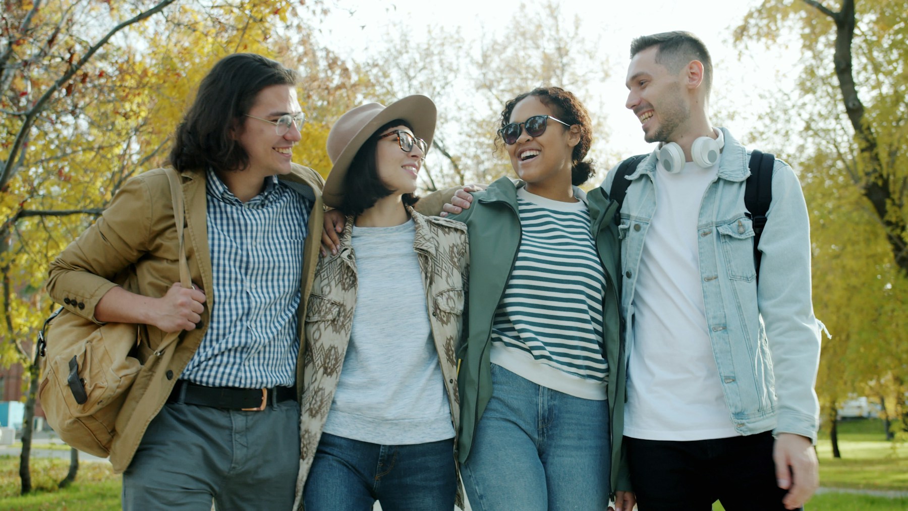 Four friends smiling as they walk together in a park